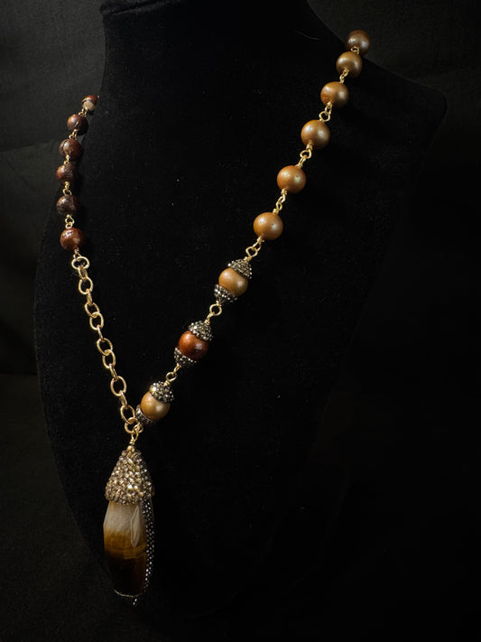 Necklace with brown beads and a decorative pendant on a black background
