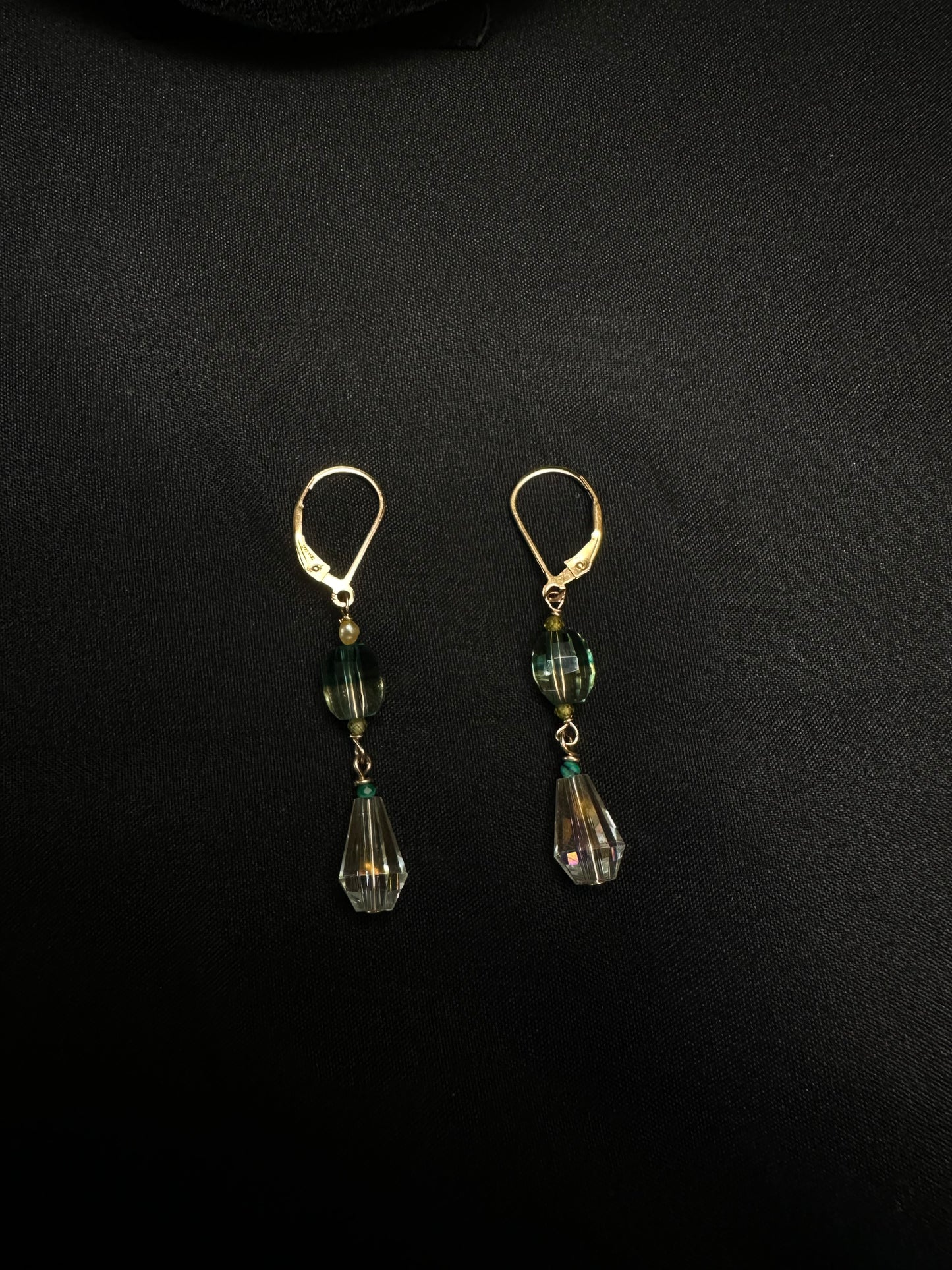 Pair of earrings with green teardrop-shaped beads on a black background