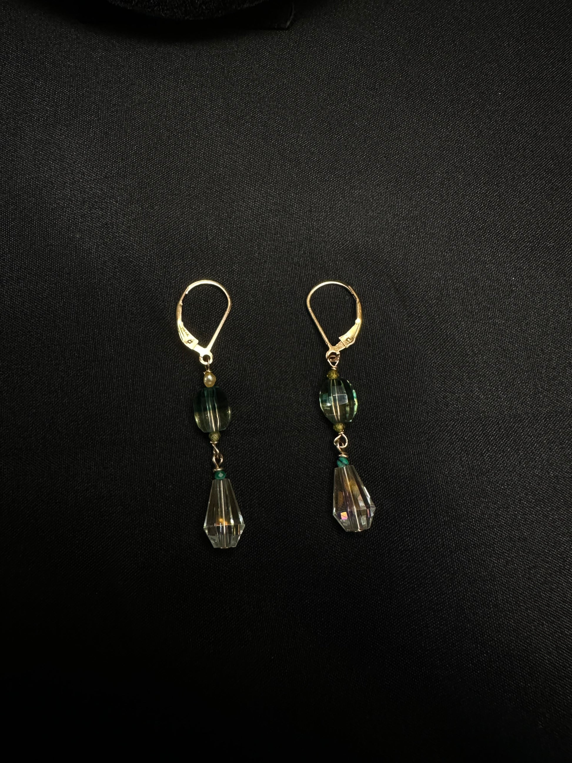 Pair of earrings with green teardrop-shaped beads on a black background