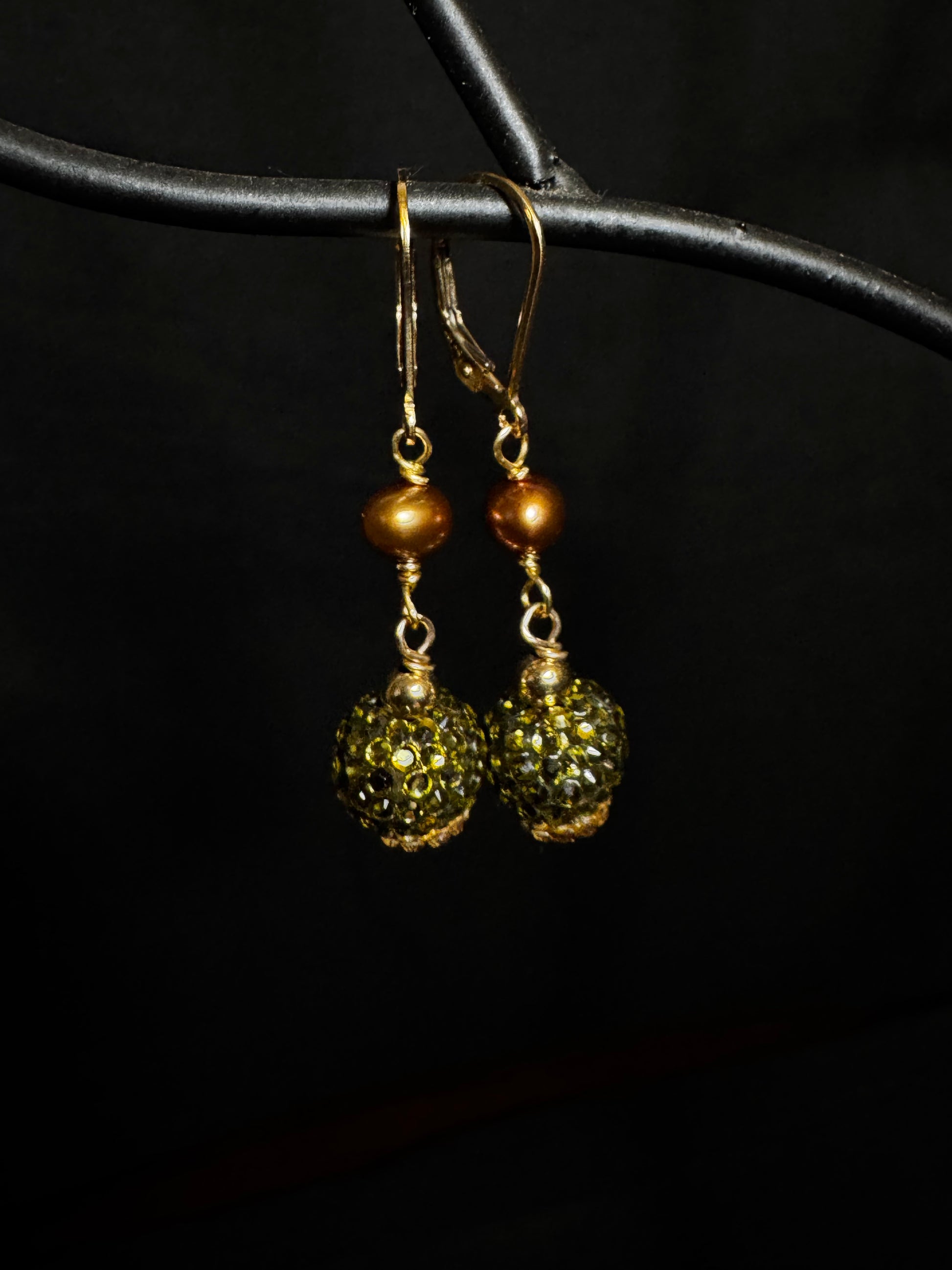 Gold and green beaded earrings on a black background
