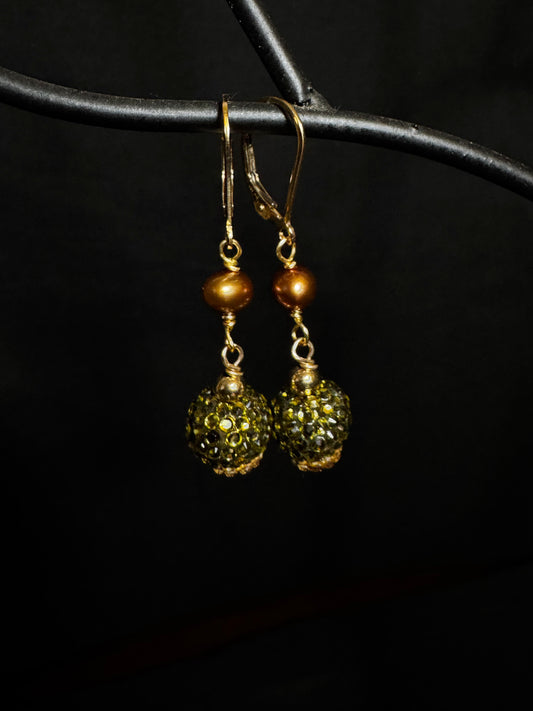 Gold and green beaded earrings on a black background
