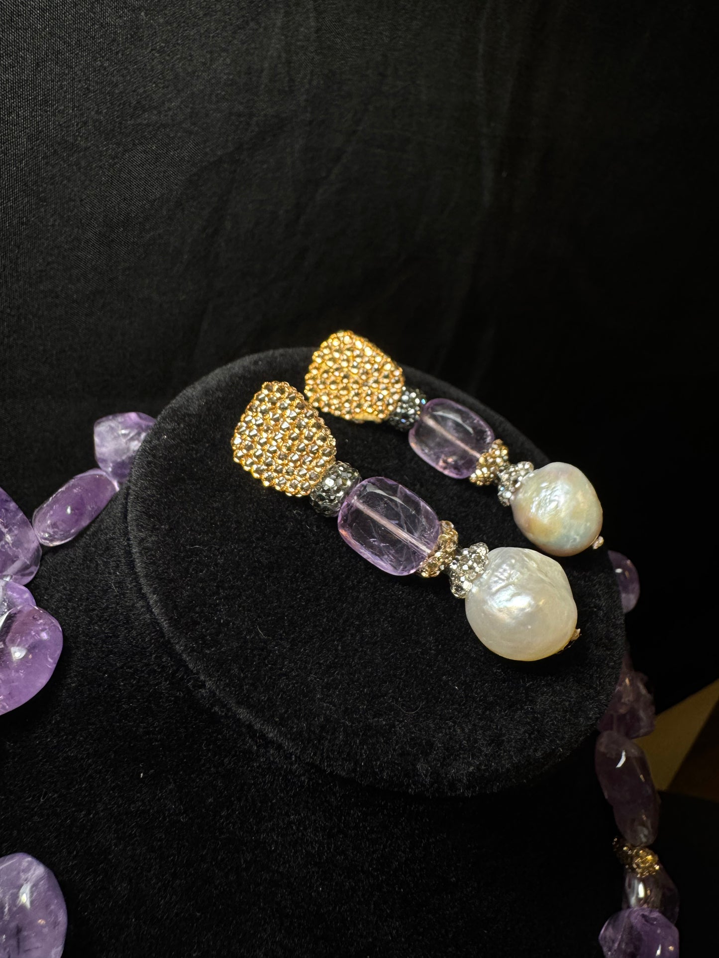 Pair of earrings with purple and gold beads on a black background