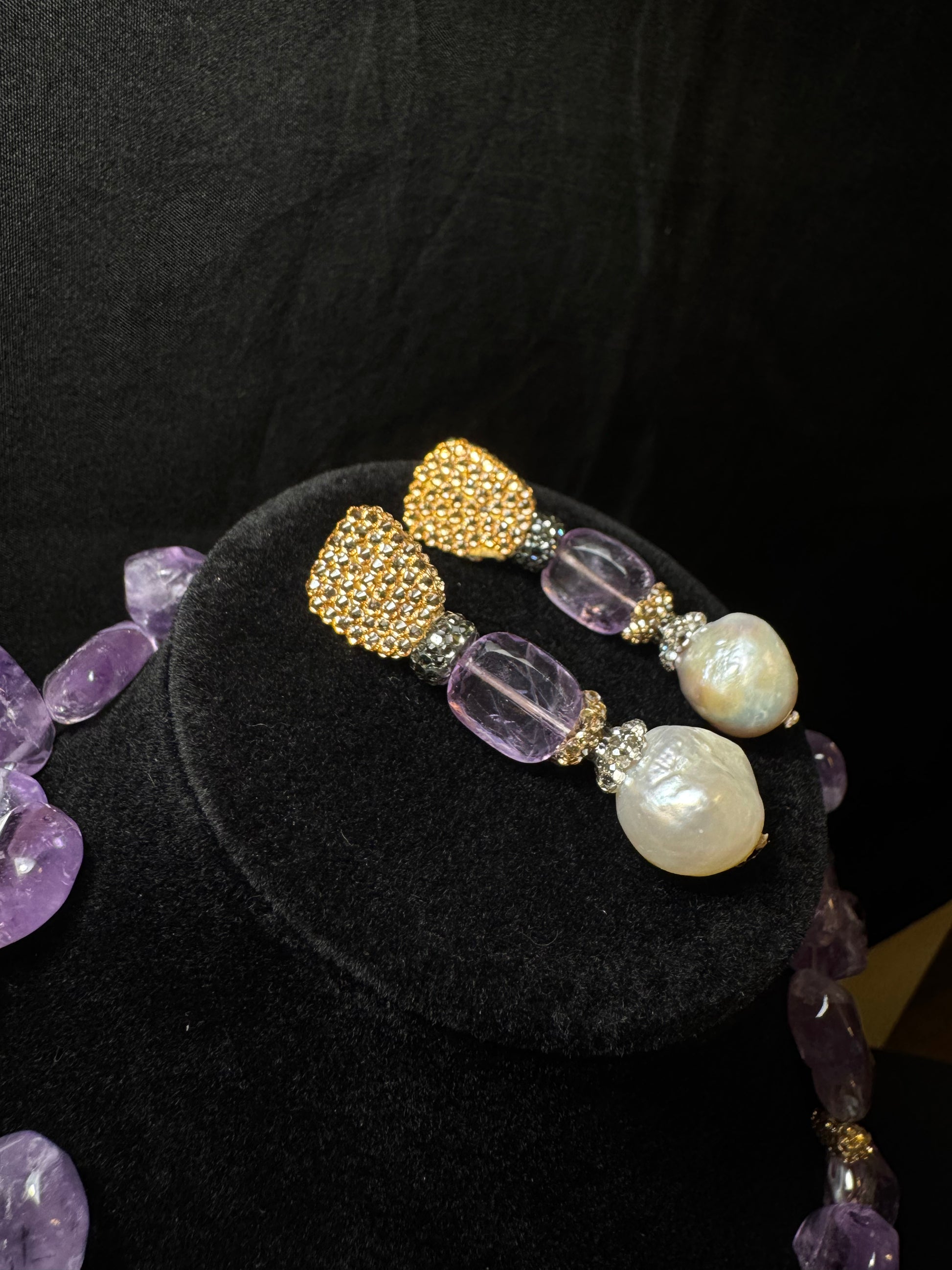 Pair of earrings with purple and gold beads on a black background