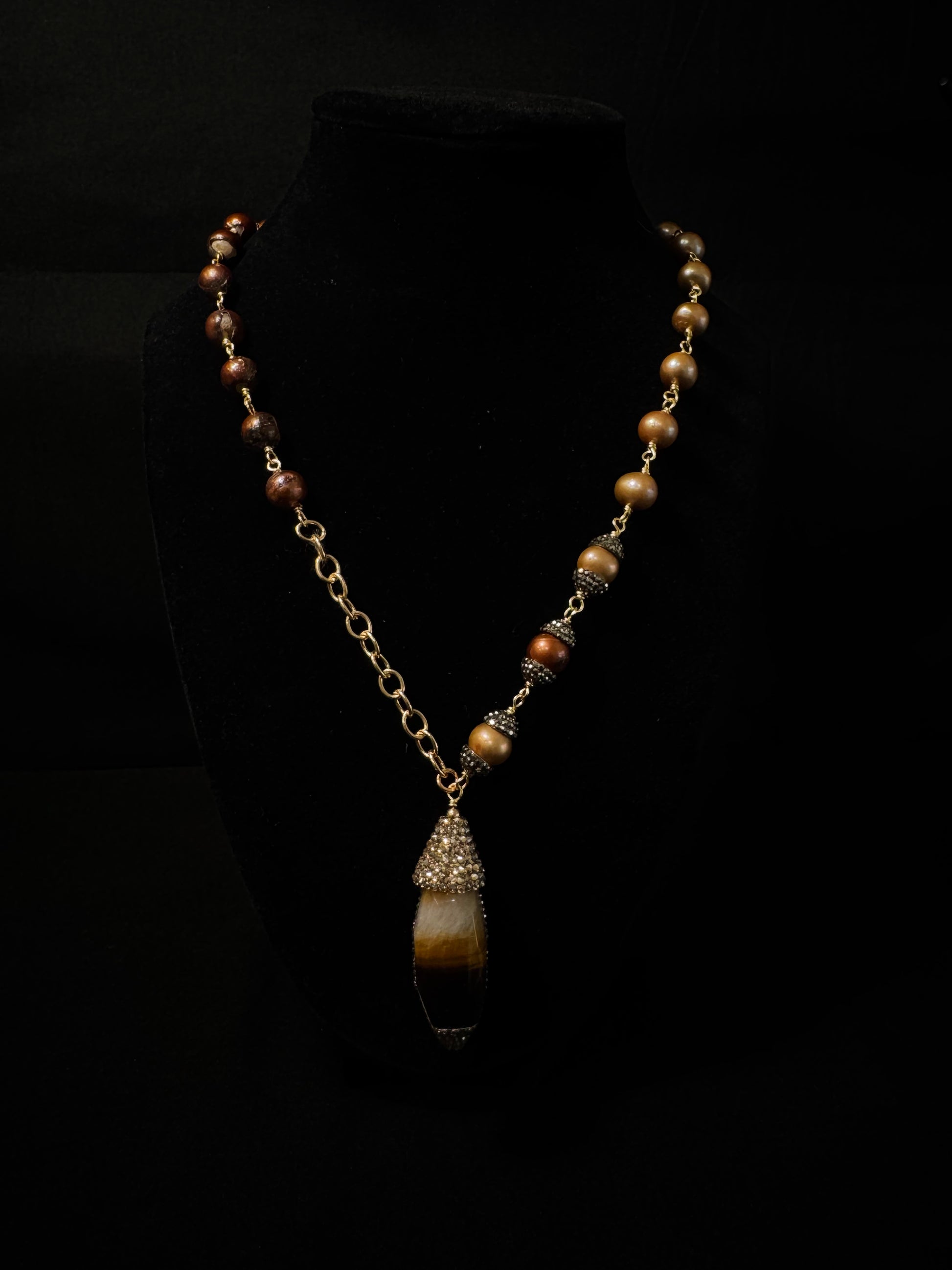 Necklace with brown beads and a pendant on a black background