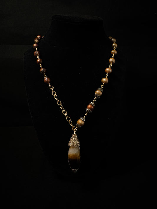 Necklace with brown beads and a pendant on a black background
