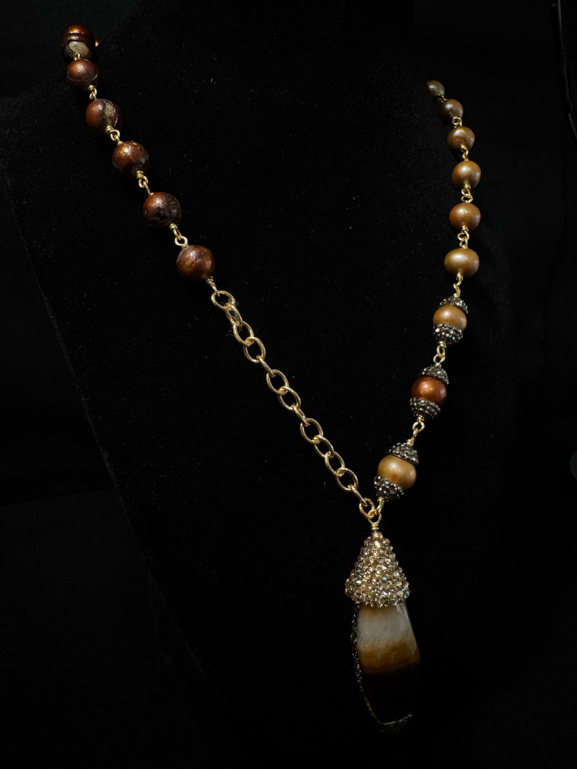 Necklace with brown beads and a pendant on a black background