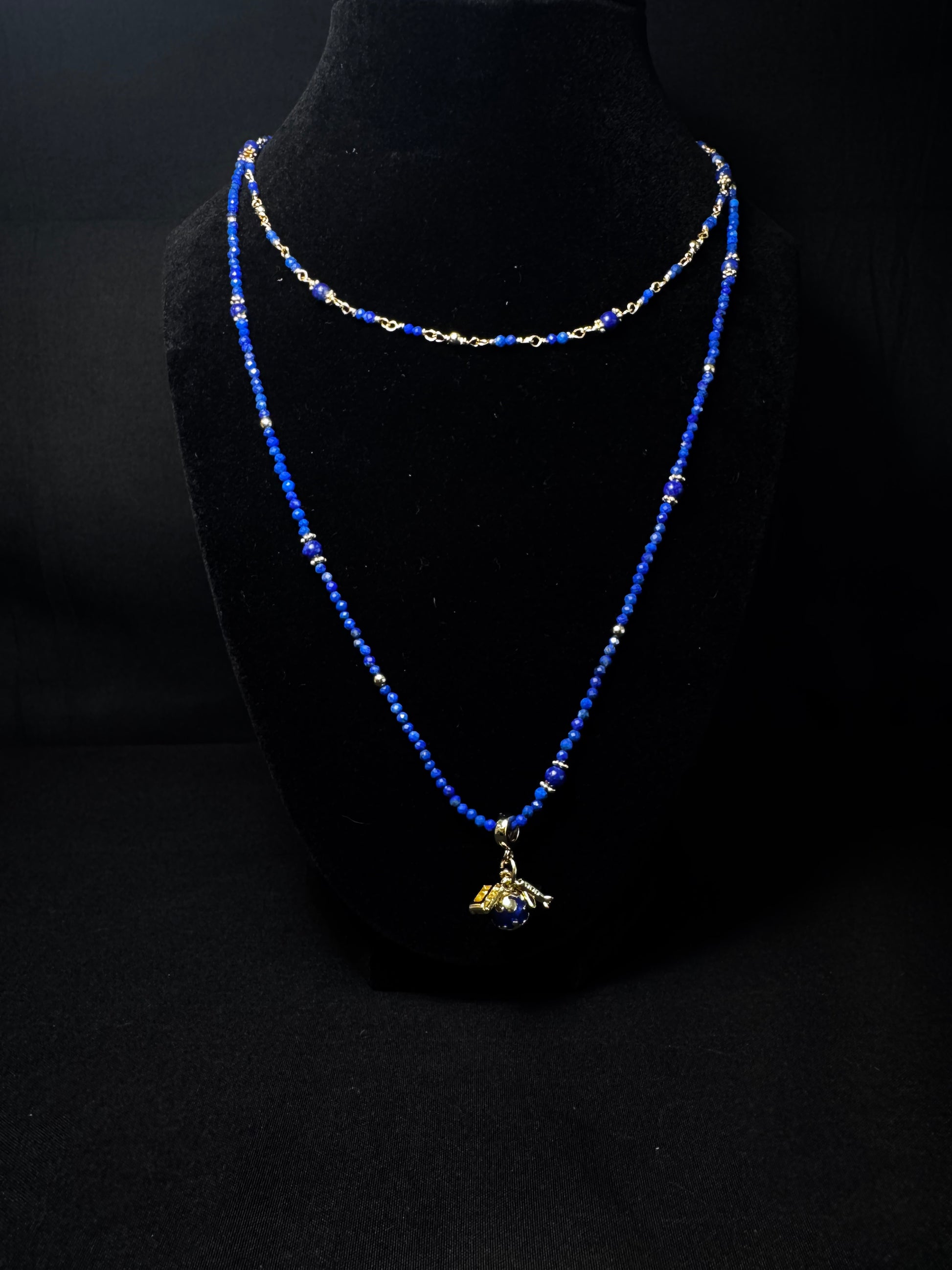 Blue beaded necklace with a pendant on a black mannequin bust