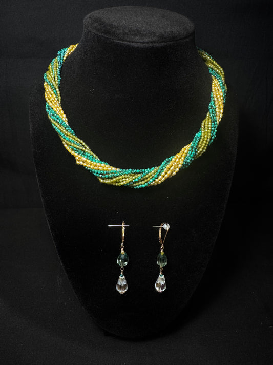 Necklace and earrings set on a black stand with a dark background