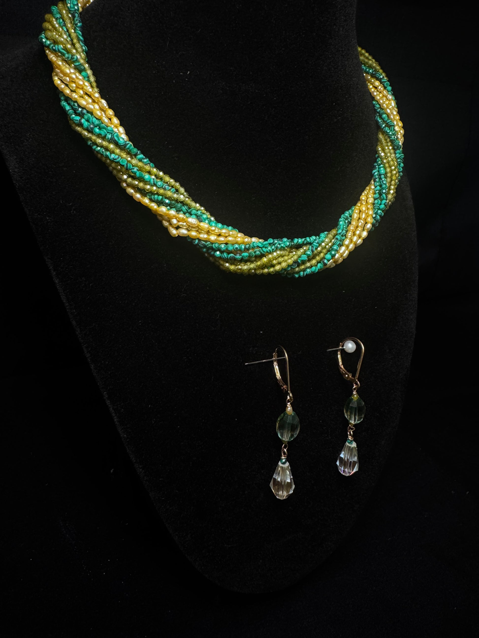 Beaded necklace and earrings on a black stand
