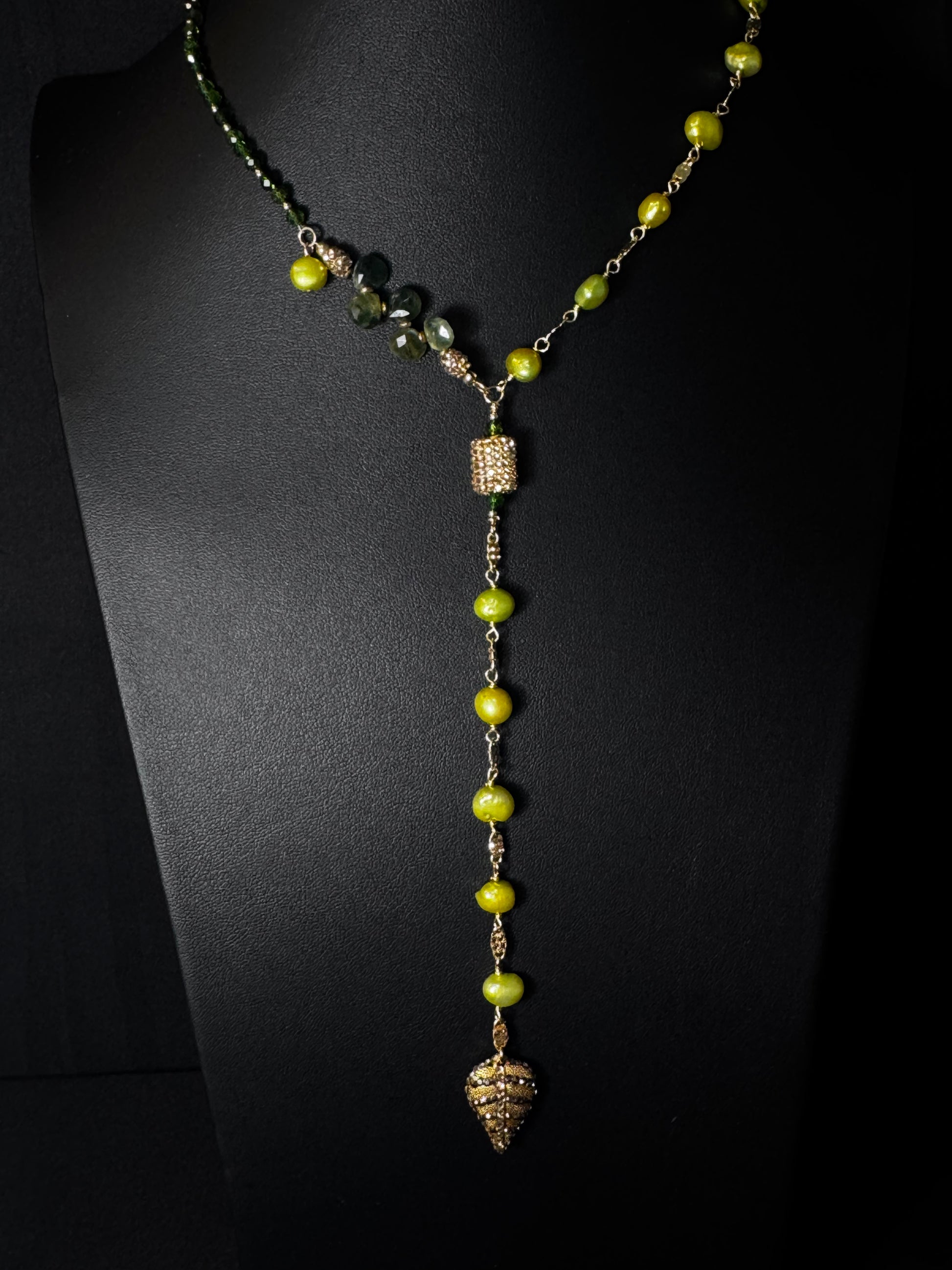 Necklace with green beads and gold accents on a black background
